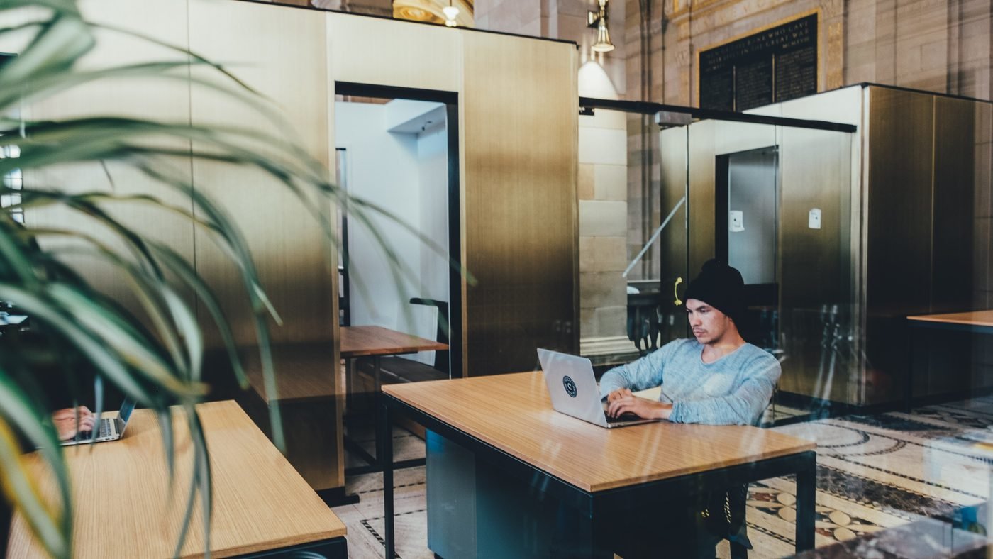 Someone working at a laptop in a glass-walled office